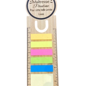 Puede incluir: Marcador de página de regla de madera con un mensaje personalizado que dice "Merci Maitresse Pauline Pour cette belle année Louise". El marcador tiene una regla en un lado y cinco notas adhesivas de colores en el otro.
