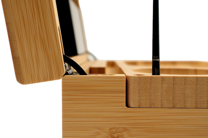 K&ouml;nnte beinhalten: Eine Bambus-Weinpr&auml;sentationsbox, teilweise ge&ouml;ffnet, die eine schwarze Weinflasche und einen schwarzen Stift zeigt. Die Box hat F&auml;cher f&uuml;r Zubeh&ouml;r. Die Holzmaserung ist sichtbar.