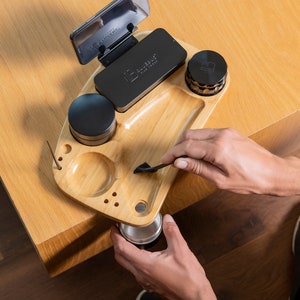May include: A wooden rolling tray with a black grinder, a small black container, a black phone holder, and a small metal container. The tray has a small compartment for a lighter and a small hole for a poker.