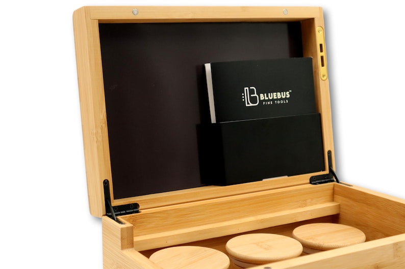 K&ouml;nnte beinhalten: Offene Bambusbox mit schwarzem Innenraum und Klappdeckel. Im Inneren befindet sich eine schwarze Tasche mit einer wei&szlig;-schwarzen Karte mit dem Text "BLUEBUS FINE TOOLS". Drei runde Untersetzer aus Holz sind unten sichtbar.