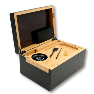 K&ouml;nnte beinhalten: Eine schwarze und nat&uuml;rliche Holzkiste mit offenem Deckel, die ein Tablett mit Werkzeugen und einer Sch&uuml;ssel freigibt. Die Kiste hat eine schwarze Au&szlig;enseite und eine Innenseite aus Naturholz. Das Tablett enth&auml;lt eine B&uuml;rste, einen Poker und ein kleines goldfarbenes Werkzeug.