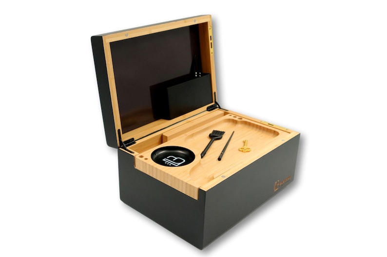 K&ouml;nnte beinhalten: Eine schwarze und nat&uuml;rliche Holzkiste mit offenem Deckel, die ein Tablett mit Werkzeugen und einer Sch&uuml;ssel freigibt. Die Kiste hat eine schwarze Au&szlig;enseite und eine Innenseite aus Naturholz. Das Tablett enth&auml;lt eine B&uuml;rste, einen Poker und ein kleines goldfarbenes Werkzeug.