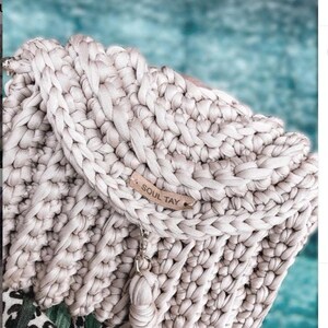 May include: A close-up of a beige crocheted bag with a brown leather tag that says "Soul Tay".