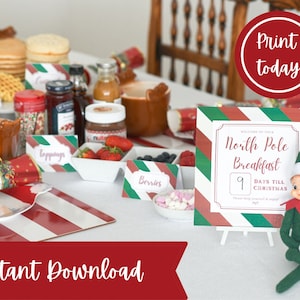 May include: A festive Christmas breakfast scene with pancakes, berries, and toppings. A sign reads "North Pole Breakfast" with 9 days until Christmas. Includes a red and white striped table setting and an elf figurine.