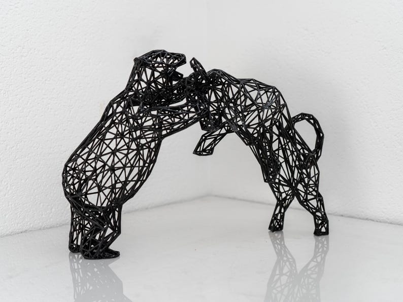 Pode incluir: Uma escultura de arame preto de um touro e um urso frente a frente. A escultura &eacute; feita de arame preto fino e &eacute; muito detalhada. O touro est&aacute; a carregar contra o urso, e o urso est&aacute; a defender-se.