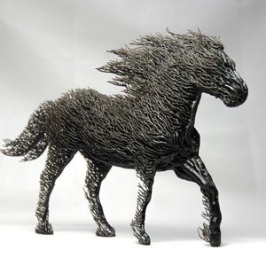 Peut inclure: Sculpture détaillée d'un cheval en mouvement, réalisée en métal sombre. La crinière et la queue du cheval flottent, capturant le mouvement. L'œuvre est placée sur un fond uni, mettant en valeur les détails complexes du travail du métal.