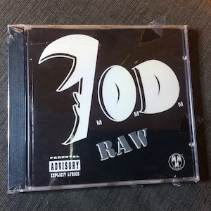 May include: A black CD case with a white graphic of the word "7OD" and the word "RAW" in white letters. The case has a parental advisory sticker with the text "Parental Advisory Explicit Lyrics".