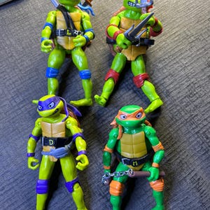 Puede incluir: Una taza de cerámica blanca con un asa negra y el texto "But First, Coffee" en negro, con una fuente de estilo manuscrito. La taza está sobre una superficie blanca.