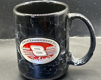 Può includere: Tazza da caffè nera con un motivo bianco simile al marmo. La tazza presenta un logo Dale Earnhardt Jr. Budweiser con il numero 8 in rosso e bianco. La tazza ha un manico grande.