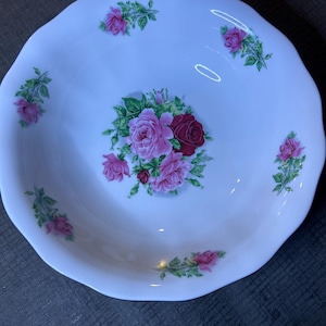 May include: White ceramic bowl with a scalloped rim and a floral design featuring pink and red roses with green leaves.