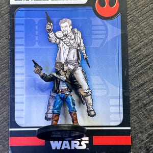 May include: A Star Wars trading card featuring two figures in combat poses. The card has the text "ELITE REBEL COMMANDO" at the top. The figures are in a blue and white background. The bottom of the card has the word "WARS".