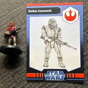 Puede incluir: Una figura en miniatura de Bothan Commando y una tarjeta coleccionable de Star Wars. La miniatura es roja y marrón, sosteniendo un arma. La tarjeta presenta una ilustración de Bothan Commando, el logo de Star Wars y el texto "Bothan Commando."