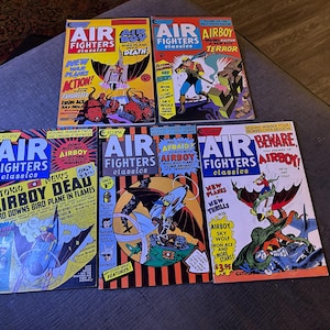 May include: A collection of vintage "Air Fighters Classics" comic books. The covers feature vibrant illustrations of aerial combat, with titles like "Airboy Death" and "Airboy Terror." The comics are in various conditions, with visible wear.
