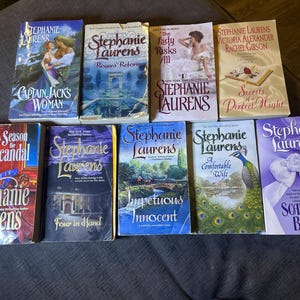 May include: A collection of ten romance novels by Stephanie Laurens. The books feature various titles, including "Captain Jack's Woman", "Rogue's Reform", "The Lady Risks All", "Secrets of a Perfect Night", "A Season for Scandal", "Four in Hand", "Impetuous Innocent", "A Comfortable Wife", and "Scandal's Bride".
