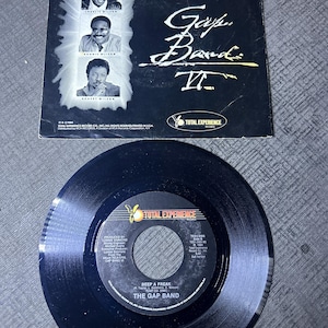 May include: A black vinyl record with the text "BEEP A FREAK" and "THE GAP BAND" printed on the label. The record is from the album "Gap Band II" and was produced by Lonnie Simmons. The record is a 45 RPM single.