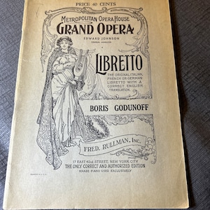 May include: A vintage, tan-colored booklet with black text and illustrations. The title is "Metropolitan Opera House Grand Opera" with the text "Libretto" in a large, decorative font. The booklet is for the opera "Boris Godunoff" and includes the text "The original Italian, French or German Libretto with a correct English translation."