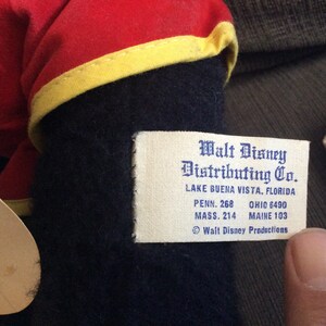 May include: White tag with black text that reads "Walt Disney Distributing Co. Lake Buena Vista, Florida Penn. 268 Ohio 6490 Mass. 214 Maine 103 &copy; Walt Disney Productions"