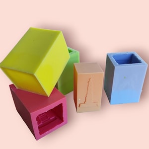Puede incluir: Cuatro moldes de silicona para hacer jabón o velas. Los moldes son de diferentes colores: amarillo, verde, naranja y azul. El molde naranja tiene un diseño de faro.