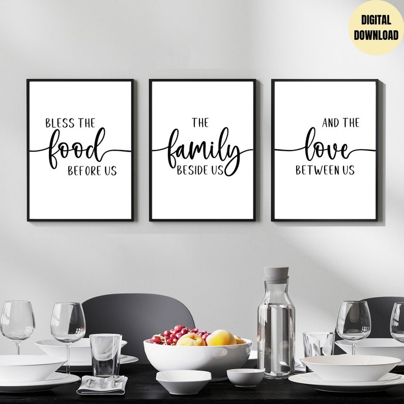 K&ouml;nnte beinhalten: Drei schwarze gerahmte Drucke mit wei&szlig;en Hintergr&uuml;nden und schwarzer Kalligraphie. Die Drucke lauten "Bless the food before us", "The family beside us" und "And the love between us".