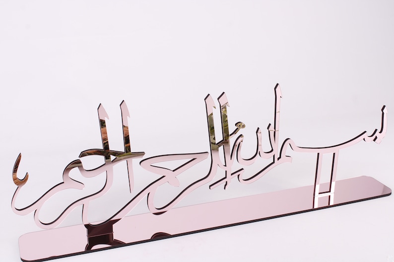 May include: A rose gold mirrored acrylic wall decor with the Arabic phrase "Mashallah" in a decorative font.