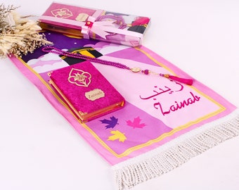 Peut inclure: Un tapis de prière rose avec une frange blanche, un livre de prière rose avec des garnitures dorées et un chapelet rose avec un charme doré. Le tapis de prière porte le nom "Zainab" écrit en caractères arabes et le nom "Zainab" écrit en anglais.