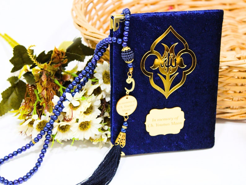 K&ouml;nnte beinhalten: Ein Gebetsbuch aus blauem Samt mit goldenen Akzenten und einem Quasten. Das Buch tr&auml;gt eine goldene Inschrift mit dem Text "In memory of Ch Younus Moon". Eine blaue Perlenkette zum Beten ist im Lieferumfang enthalten.