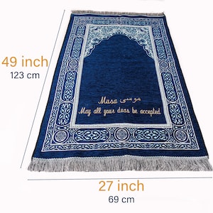 May include: A navy blue prayer mat, 123 cm long and 69 cm wide, with a decorative border and an arched design. The mat has text in Arabic and English that reads "Musa" and "May all your duas be accepted."