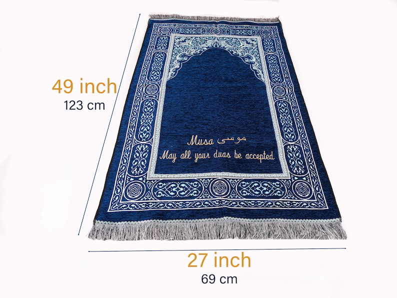 May include: A navy blue prayer mat, 123 cm long and 69 cm wide, with a decorative border and an arched design. The mat has text in Arabic and English that reads "Musa" and "May all your duas be accepted."
