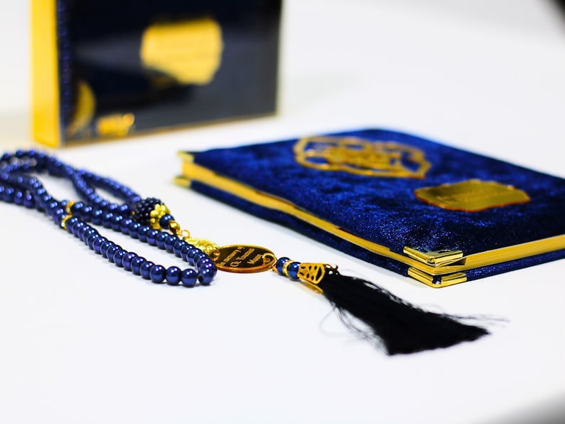 K&ouml;nnte beinhalten: Ein Gebetbuch aus blauem Samt mit goldenen Akzenten und dazu passende blaue Gebetsperlen mit einem goldenen Quast.