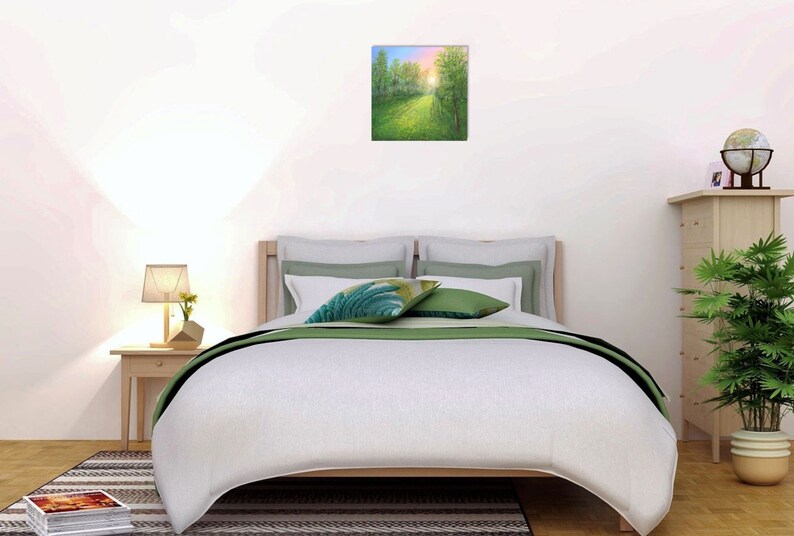 Puede incluir: Una pintura cuadrada de una escena de bosque soleado cuelga sobre una cama con ropa de cama blanca y detalles en verde. Una peque&ntilde;a mesita de noche con una l&aacute;mpara y una planta est&aacute; a la izquierda. Un globo terr&aacute;queo y una planta est&aacute;n a la derecha.