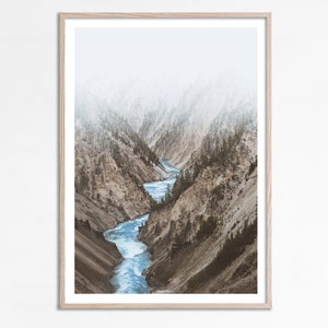 May include: A photograph of a river winding through a canyon with misty mountains in the background.