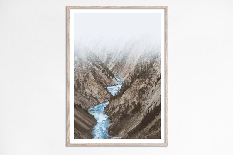 May include: A photograph of a river winding through a canyon with misty mountains in the background.