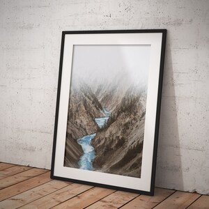 May include: A framed photograph of a river winding through a mountain canyon. The photo is in black and white with a muted blue river.