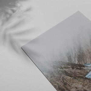 May include: A photograph of a mountain range with a narrow valley in the center. The valley is filled with fog and the mountains are covered in snow. The image is taken from a low angle, looking up at the mountains.