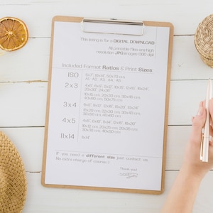 May include: A clipboard with a list of different print sizes for digital downloads. The list includes sizes like 5x7, 10x14, 4x6, 6x10, 12x18, 18x24, 20x30, 24x30, 10x20, 10x24, 15x20, 22x30, 30x40, 30x50, 45x80, 10x12, 20x25, 20x30, 30x30, 40x50, 8x14 inches. The clipboard is on a white wooden surface with a straw hat, wheat stalks, and dried orange slices.