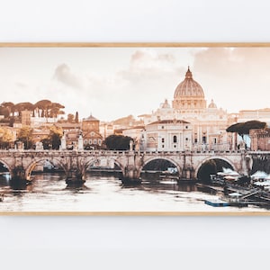 May include: A panoramic view of the city of Rome, Italy, featuring the iconic dome of St. Peter's Basilica in the background. A stone bridge crosses the River Tiber in the foreground, with the city skyline visible beyond.