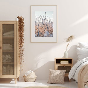 May include: A framed photograph of a field of lavender flowers in shades of purple and brown. The photo is hanging on a white wall in a bedroom setting.