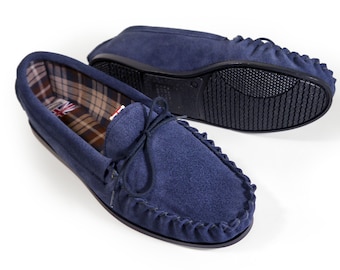May include: A pair of blue suede moccasins with a plaid lining. The moccasins have a rubber sole and a decorative fringe around the edge.