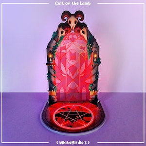 May include: A decorative acrylic stand featuring a stylized red and pink stained-glass door with a pentagram on the base. The stand has a skull design at the top and the text "Cult of the Lamb" is visible at the top.