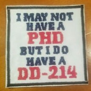 Könnte beinhalten: Weißer Patch mit schwarzem Rand, mit dem Text "I may not have a PHD but I do have a DD-214" in blauer und roter Schrift.