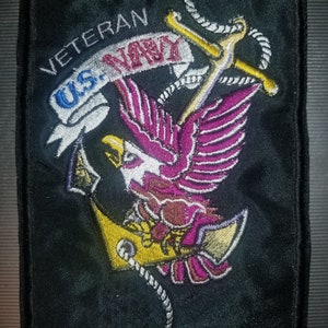 May include: A black embroidered patch with a yellow anchor, a pink eagle, and the text "Veteran U.S. Navy".