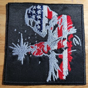 Può includere: Toppa ricamata con un saldatore che indossa una maschera da saldatura e tiene in mano una torcia da saldatura. Il saldatore è raffigurato nei colori della bandiera americana, rosso, bianco e blu.