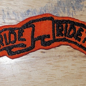 May include: Orange and black embroidered patch with the text "Live to Ride, Ride to Live".