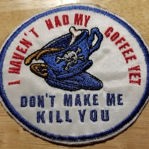 May include: White embroidered patch with blue and red trim. It features a blue and white coffee cup with a skull and crossbones and the text "I haven't had my coffee yet. Don't make me kill you."