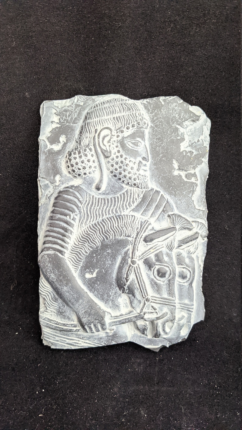 May include: A white plaster relief sculpture of a man on horseback. The man is wearing a helmet and armor, and the horse is wearing a bridle. The sculpture is set against a dark background.