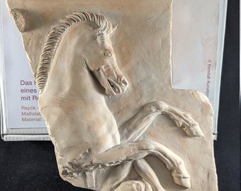 Può includere: Una scultura in gesso bianco a rilievo di un cavallo che si impenna sulle zampe posteriori, con una figura umana sdraiata sotto. La scultura è montata su una base di pietra con testo greco inciso su di essa. Il testo recita: "ΕΝΔΕΚΑΙΓΑΤΡΙΣ ΓΙΕΓΙΟΛΛΟ ΣΩΛΕΣΑΣΜΑ ΔΟΞΙΑΟΥΡΕΣΟΣΣΑΡΕΛΙΣΤΗΣΑΓΡΟΓΑΙΑΙΑ ΛΟΕΦΛΥΕΥΣ".