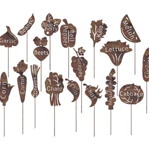 May include: A set of 16 metal garden markers with rusty brown finish. Each marker features a different vegetable or fruit, including corn, beans, garlic, beets, carrot, chives, chard, grapes, bell pepper, chili, brussel sprouts, kale, lettuce, cabbage, melon, and cucumber.