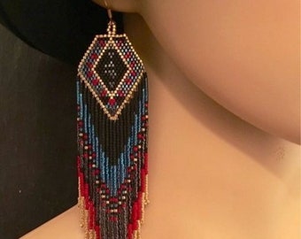 May include: Handmade beaded earrings with a geometric design. The earrings feature a diamond-shaped top with black, red, and gold beads. Below, the earrings cascade into a fringe of red, blue, and gold beads, creating a striking visual effect.