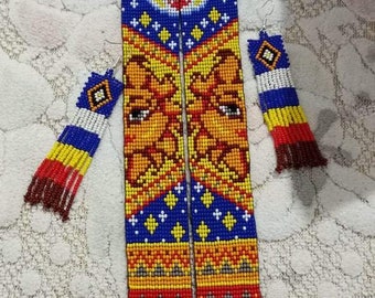May include: A long, beaded necklace with a blue, yellow, orange and white pattern. The necklace features two faces, one of the sun and one of the moon. The necklace is paired with matching earrings.