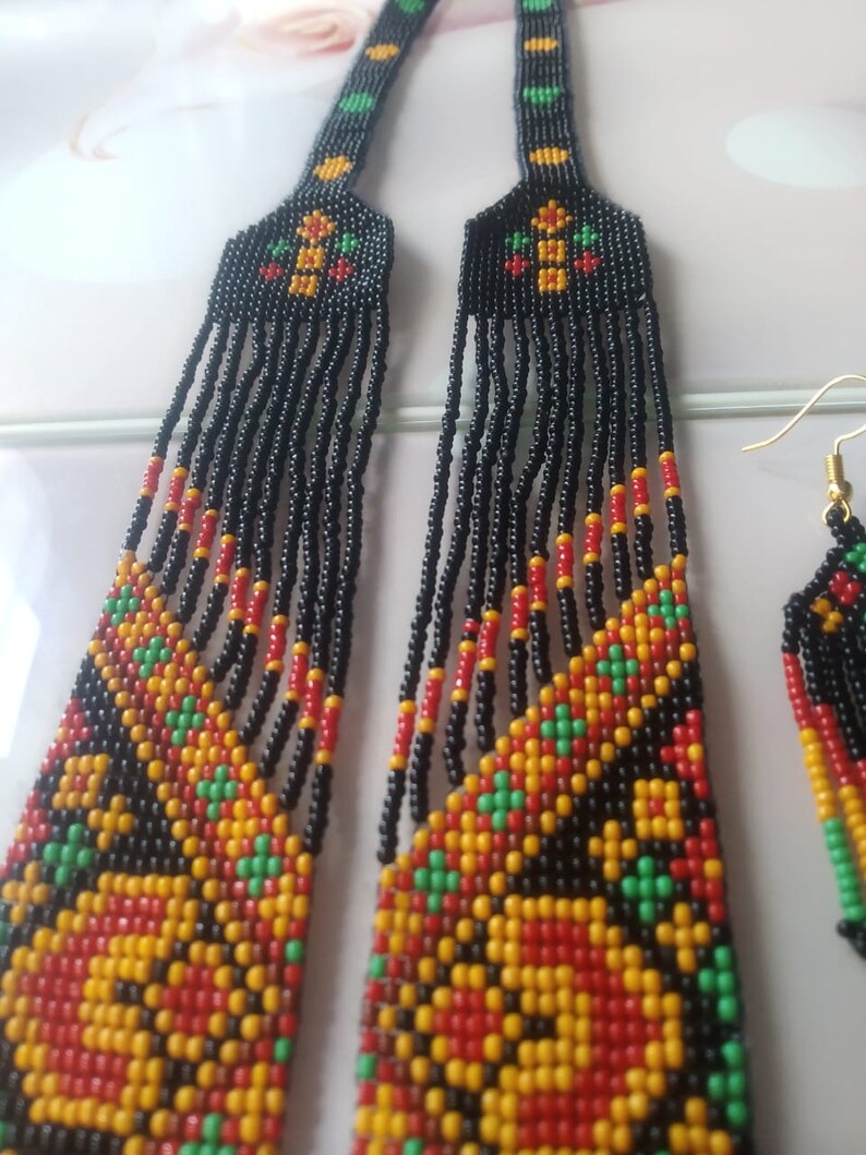 May include: A black beaded necklace and earrings set with a geometric pattern in red, yellow, and green.